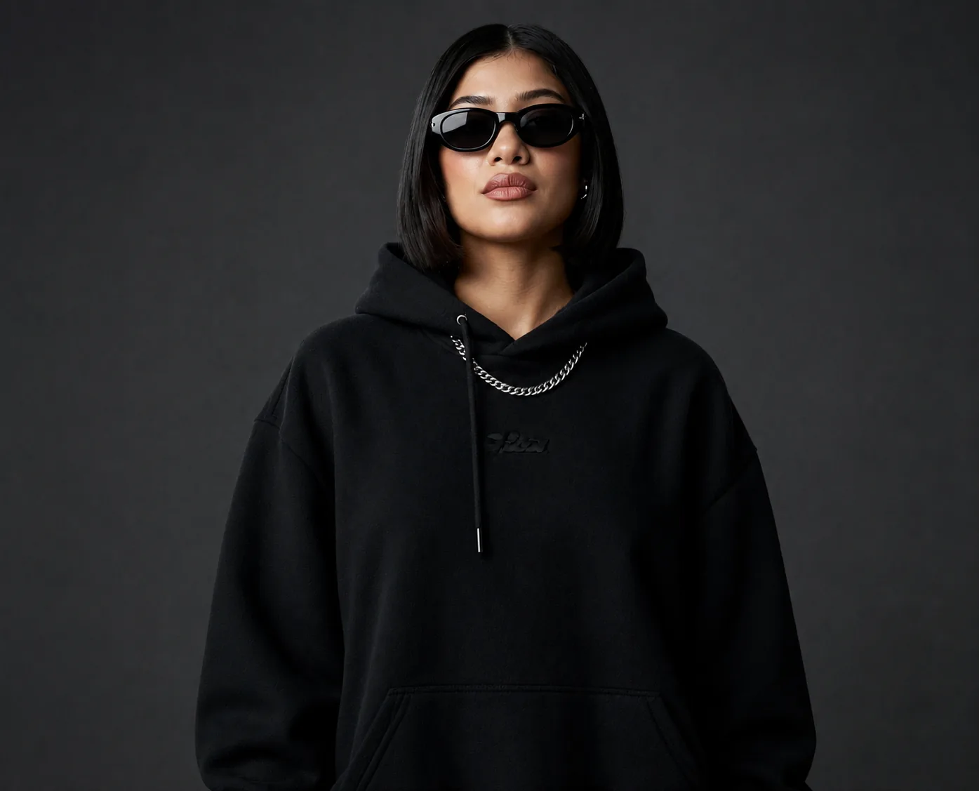 Sapience Studios apparel, a black hooded sweatshirt worn against a dark backdrop